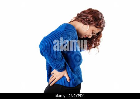 Seitenansicht einer isolierten Frau auf weißem Hintergrund mit Schmerzen im unteren Rücken. Fühlt Rückenschmerzen, massiert schmerzende Muskeln, traurig leidet fr Stockfoto