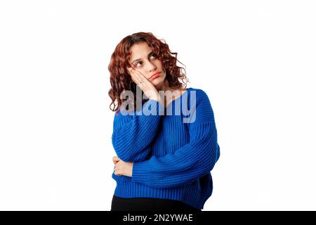 Eine junge weiße Frau, die einen Pullover trägt und isoliert auf weißem Hintergrund steht, neigt sich mit dem Kopf auf die Handfläche und sieht pessimistisch auf den leeren Kopierraum. Nein. Nein Stockfoto