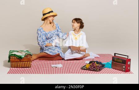 Beim Picknick. Porträt von jungen Frauen und kleinen Mädchen, Mutter und Tochter isoliert vor hellem Hintergrund. Konzept von Schönheit, Retro-Stil, Mode Stockfoto