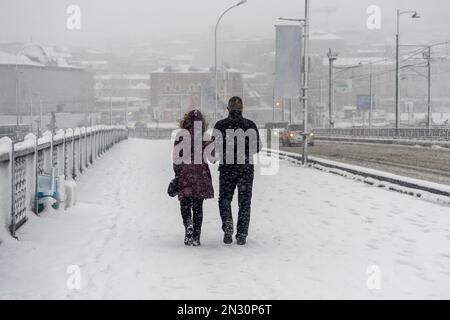 Ein Paar, das an einem nebligen, verschneiten Wintertag in Istanbul, Türkei, über die Galata-Brücke spaziert. Stockfoto