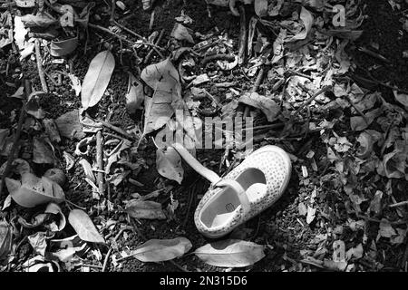 Verlorener Einzelschuh des Kindes auf dem Boden des Waldes. Verlorenes, vermisstes Kind Stockfoto