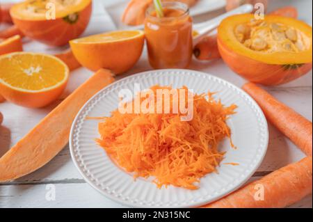 Buntes Gemüse und Früchte mit Orangenfarben auf weißem Hintergrund. Nahaufnahme und Vorderansicht Stockfoto