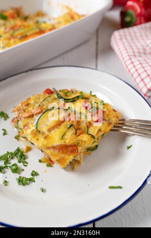Frittata mit Zucchini, Tomaten, Karotten, Zwiebeln und Paprika auf einem Teller Stockfoto