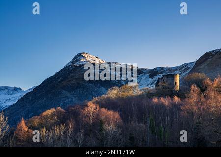 Dolbadarn Castle mit einem schneebedeckten Derlwyn Berg in der Wintersonne am späten Nachmittag, Gwynedd, Nordwales Stockfoto