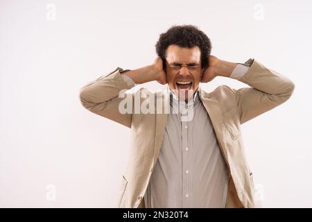 Das Bild eines frustrierten Geschäftsmannes ist, sich die Ohren zu verschließen und zu schreien. Stockfoto