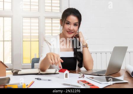 Business, Architektur, Gebäudebau und Immobilienkonzept. Eine Immobilienmaklerin präsentiert ein Hausmodell. Stockfoto