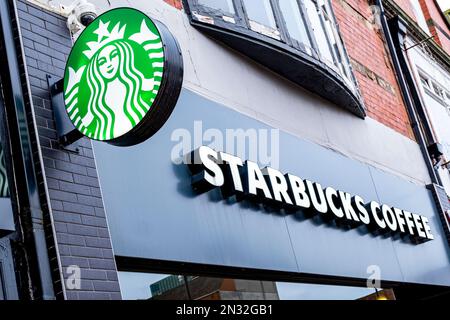 Nahaufnahme des Schilds „Starbucks Coffee“ mit Logo an der Außenwand von Großbritannien Stockfoto
