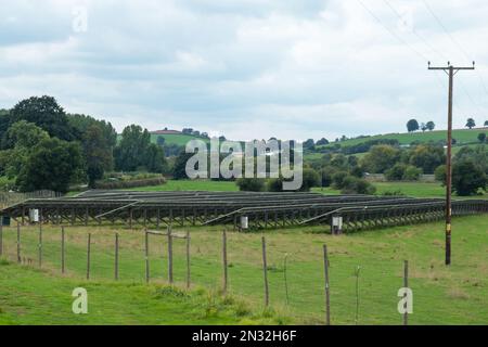 Rückansicht der Arrays von Solarpaneelen, die auf einem Bauernhof in East Devon, Großbritannien, installiert sind und das nationale Energienetz versorgen Stockfoto