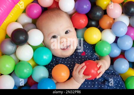 Glückliches Kind in einer Ballgrube. Kleines Mädchen mit einem Ball. Stockfoto