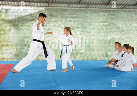 Ein Mädchen, das Karate mit Trainer auf Tatami im Freien übt Stockfoto