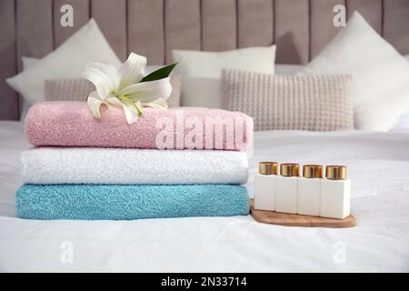 Ein Stapel sauberer Handtücher, Blumen- und Shampooflaschen auf dem Bett Stockfoto