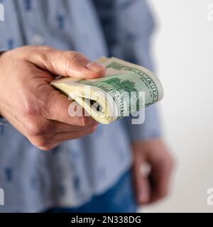 Ein Mann überreicht einen dicken Haufen Dollar Stockfoto