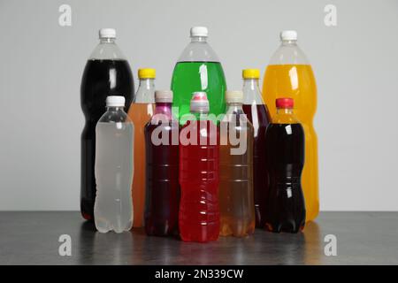 Flaschen mit alkoholfreien Getränken auf dem Tisch vor grauem Hintergrund Stockfoto