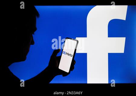 Vilnius, Litauen - 2022. Februar 6: Facebook- und Meta-Firmenlogo auf Smartphone- und PC-Bildschirmen. Männersilhouette mit facebook-App in der Hand Stockfoto