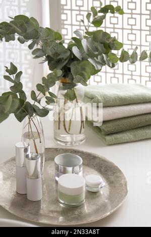 Frische Eukalyptusäste und Kosmetikprodukte auf der Arbeitsfläche im Badezimmer Stockfoto