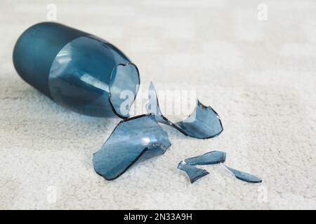 Zerbrochene blaue Glasvase auf Teppich, Nahaufnahme Stockfoto