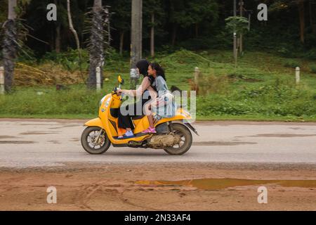 Mutter und Tochter, die auf dem Land Motorrad fahren. Ko Lanta, Krabi, Thailand. 4. Dezember 2022. Stockfoto