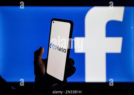 Vilnius, Litauen - 2022. Februar 6: Facebook- und Meta-Firmenlogo auf Smartphone- und PC-Bildschirmen. Ein Mann, der die facebook-App in der Hand hält Stockfoto