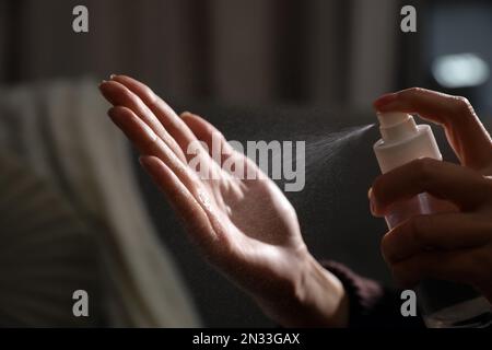 Frau, die Antiseptikum auf die Hand sprüht, vor verschwommenem Hintergrund, Nahaufnahme Stockfoto