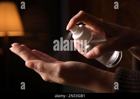 Frau, die Antiseptikum auf die Hand sprüht, vor verschwommenem Hintergrund, Nahaufnahme Stockfoto