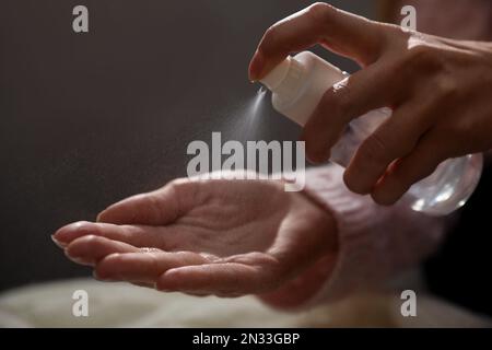 Frau, die Antiseptikum auf die Hand sprüht, vor verschwommenem Hintergrund, Nahaufnahme Stockfoto