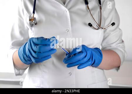 Medizinische Krankenschwester oder Arzt in Sicherheitshandschuhen Öffnen Impfstoff Injektion Injektionsnadel und Spritze, um eine Droge als Behandlung in einer Gesundheitsklinik zu geben Stockfoto