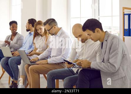 Geschäftsleute, die an Seminarschulungen teilnehmen und in Paaren diskutieren, um Aufgaben mithilfe von Laptops gemeinsam zu erledigen. Stockfoto