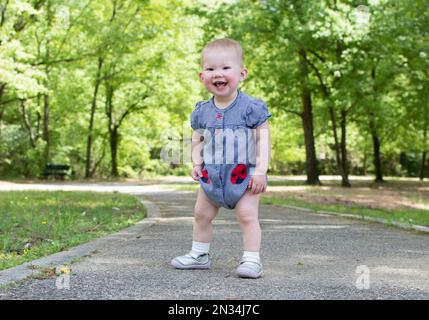 Süßes, weißes Baby, das die ersten Schritte im Park macht. Gehen eines Kleinkindes Stockfoto