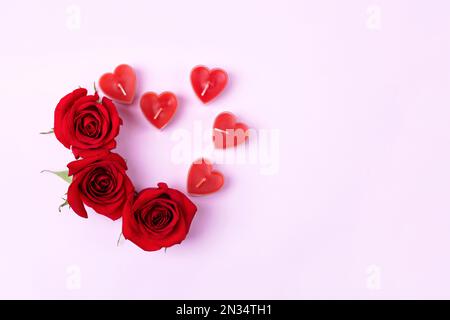 Romantischer Hintergrund mit Platz für Text. Rote Rosen und Kerzen in Herzform. Valentinstag-Konzept. Flach verlegt Stockfoto