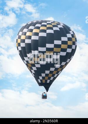 Heißluftballon, der gegen den hellblauen Himmel fliegt Stockfoto