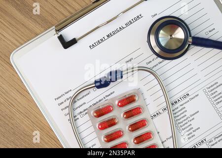 Stethoskop und medizinische Pillen auf leerer Patientenanamnese Formular an Klemmbrett angeheftet. Stockfoto