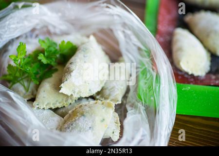 Rohe, grüne Teigknödel mit Petersilie, Dill. Rohe Knödel in einer Tüte auf einem Holztisch. Stockfoto