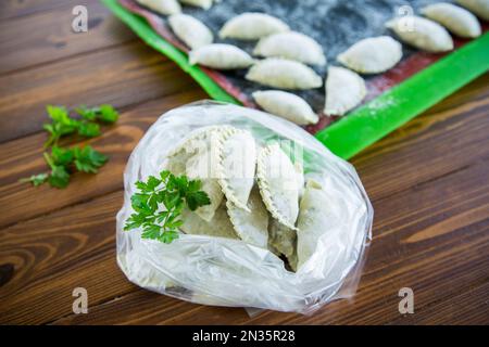 Rohe, grüne Teigknödel mit Petersilie, Dill. Rohe Knödel in einer Tüte auf einem Holztisch. Stockfoto