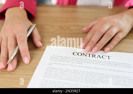 Weibliche Managerin bittet um Vertragsunterzeichnung, während sie im Büro am Schreibtisch sitzt. Stockfoto