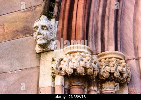 Kunstvoll geschnitzter Steinkopf und Gesicht an der Außenseite eines Kircheneingangs. Stockfoto