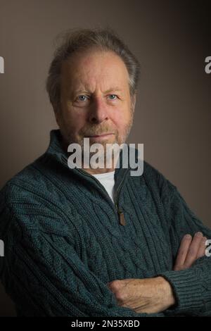 Kopf- und Schulterporträt eines attraktiven älteren, älteren weißen Mannes in einem grob gestrickten Pullover mit Zopfmuster Stockfoto