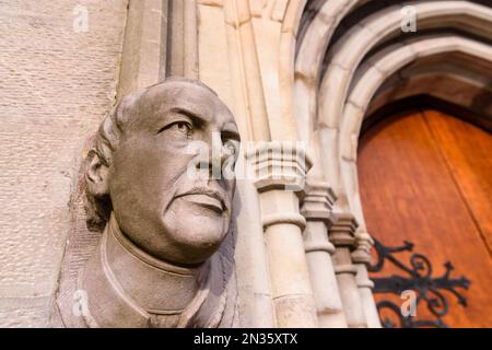 Kunstvoll geschnitzter Steinkopf und Gesicht an der Außenseite eines Kircheneingangs. Stockfoto