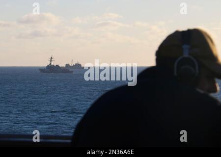 ATLANTIK (4. Februar 2023) Seemann Rafael Mendez steht an Bord des Landungsschiffs USS Carter Hall (LSD 50) und beobachtet, wie der Zerstörer USS Oscar Austin (DDG 79) und der Kreuzschiff USS Philippine Sea (CG 58) zusammen mit Trümmern aus einem großen Überwachungsballon umherfahren. Carter Hall ist das führende Schiff bei der Rückgewinnung von Trümmern, geleitet von der Navy, in Partnerschaft mit den USA Küstenwache mit mehreren Einheiten zur Unterstützung der Bemühungen, einschließlich Schiffen, Flugzeugen und einer mobilen Sprengstoffentsorgungseinheit für Sprengstoffe. Stockfoto