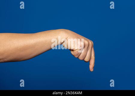 Starke Hand eines Mannes, der mit dem Zeigefinger nach unten zeigt, isoliert auf blauem Hintergrund. Stockfoto