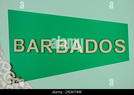 BARBADOS in englischsprachigen Großbuchstaben aus Holz, die aus einem Stapel Buchstaben auf grünem Hintergrund hervorgehen und eingerahmt sind Stockfoto