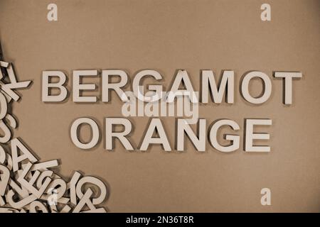 BERGAMOTORANGE in englischsprachigen Großbuchstaben aus Holz, die aus einem Stapel von Buchstaben in Sepia auslaufen Stockfoto