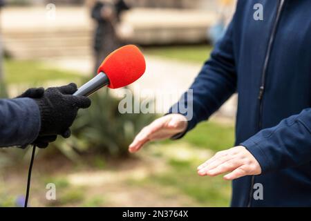 Reporter, der Medien macht, oder Vox-Pop-Interview mit einem nicht wiedererkennbaren Mann im Winter Stockfoto