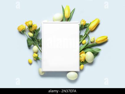 Komposition mit leerem Bilderrahmen, wunderschönen Blumen und Ostereiern auf hellem Hintergrund Stockfoto