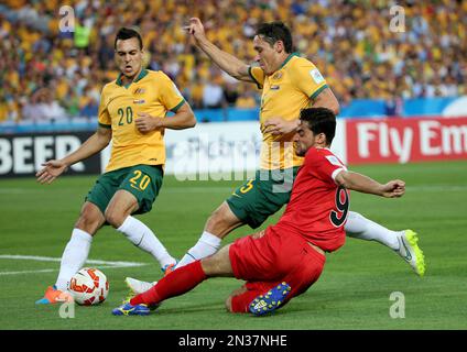 Australia's Mark Milligan, center, is tackled by Oman's Abdul Aziz Al-Maqbali, right, as teammate Trent Sainsbury looks on during the AFC Asian Cup soccer match between Australia and Oman in Sydney, Australia, Tuesday, Jan. 13, 2015. (AP Photo/Rob Griffith)