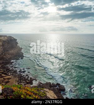 Felsige Küste, Meer und Sonnenlicht scheinen durch Wolkenlücken. Wunderschöner Naturhintergrund. Stockfoto