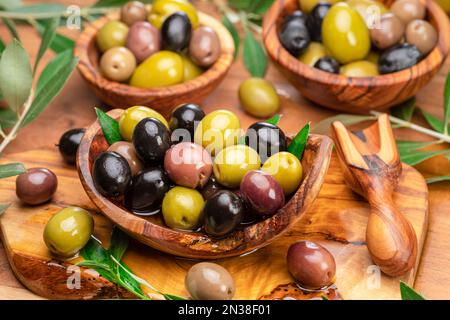 Kalamata, grüne und schwarze Oliven in den Holzteller. Hintergrund der Speisen. Stockfoto