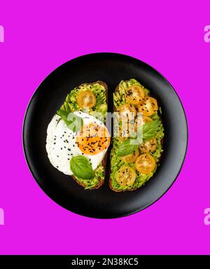 Roggentoast mit zerdrückter Avocado und pochiertem Ei auf schwarzer Platte auf isoliertem Hintergrund Stockfoto
