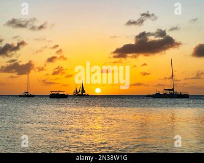 Segelboote am Horizont bei Sonnenuntergang, auf dem karibischen Meer, vor der Küste von Aruba Stockfoto