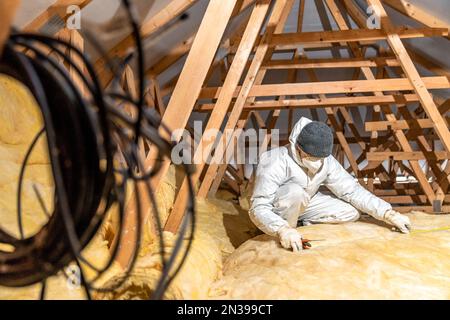 Man isoliert das Dach und die Decke des Hauses mit Glaswolle Stockfoto