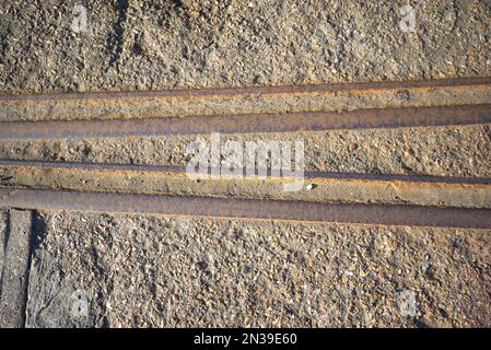 Alte rostige Eisenbahnstrecke, eingebettet in Beton Stockfoto